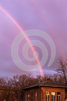 Bright multi-colored rainbow in the rays of the evening sunset sun against the sky in clouds after rain. Rainbow, Good News,