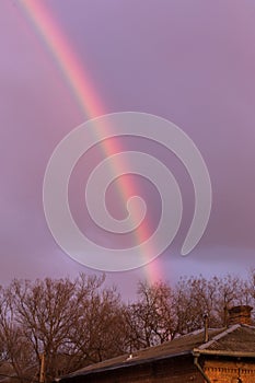 Bright multi-colored rainbow in the rays of the evening sunset sun against the sky in clouds after rain. Rainbow, Good News,