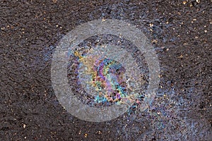 Bright multi-colored spot of spilled gasoline on the ground. Environmental pollution. Abstract background