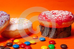 Bright multi-colored sweets on an orange background. assorted donuts with candy