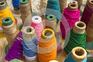 Bright multicolored spools of thread close-up stand on a  table surface against a blurred background