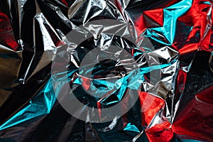 Bright neon reflex from red and blue light on the metal surface of crumpled foil, abstract holographic background