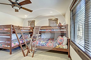 Bright new bedroom with two bunk beds with colorful bedding and ceiling fan