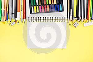 bright office and school stationary with notepad on yellow writing desk background
