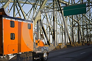 Bright orange big rig semi truck with extra space cab going on a