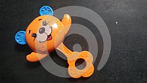 Bright orange and blue baby rattle or baby toy with teddy bear face