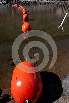 Bright orange buoy in the water behind a dam