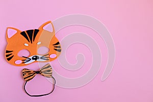 Bright orange carnival tiger mask and tiger butterfly on the neck on a pink background. Symbol of 2022