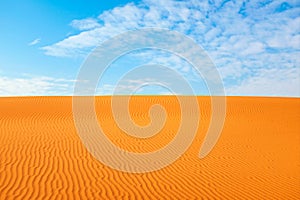 Bright orange color rippled desert sand and clear blue sky for a warm hot summer background