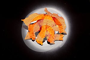 Bright, orange, crunchy, crisp snack of ripe and sweet pumpkin on a black backgroun