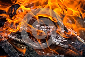 Bright orange flame and charred wood, fire close-up