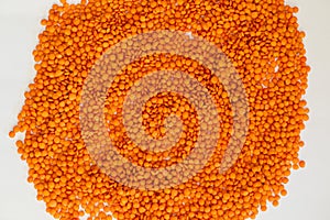 Bright orange lentils scattered on a white surface