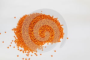 Bright orange lentils scattered on a white surface