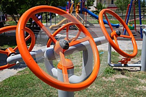 Bright orange metal steering wheels simulators on the playground