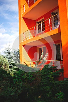 Bright orange modern building with greenery in front of windows