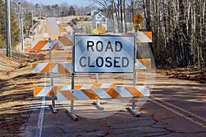A bright orange road closed ahead sign caution cones barricades are blocking