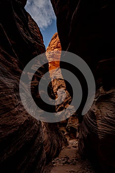 Bright Orange Rocks Pop Out At The End of A Dark Slot Canyon