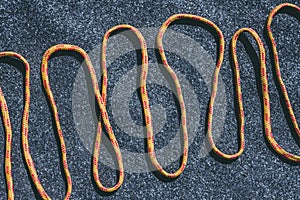 Bright orange rope on a texured roofing felt surface with many small grey stones