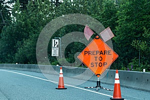 Bright orange sign that reads be prepared to stop warns a line of motorists of road construction ahead.