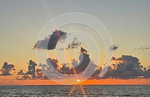 Bright orange sunset and sea beach. Sun steam and sun rays and dark romantic cloud