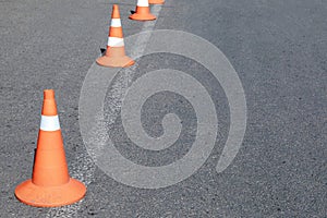 Bright orange traffic cones on asphalt road. Traffic signal cones considered universal products, with their help you can quickly