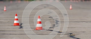 Bright orange traffic cones ready for slalom on an asphalt surface.