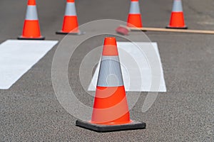 Bright orange traffic cones standing on asphalt. Painting road markings. Traffic cones for road works