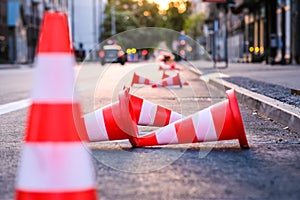 Bright orange traffic cones standing in a row on dark asphalt in the city. Road works. Selective focus