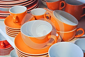 Bright orange and white dishes, plates and cups standing on whit