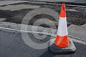 Bright orange and white traffic cone on a sidewalk