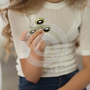 Bright photo of child with green fidget spinner in hands, white clothes and background