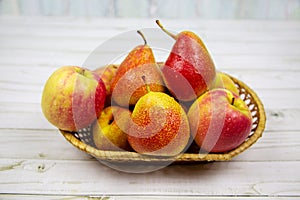 Bright pink apples and pears in a wicker basket on a table made of gray boards. Vegetables and fruits.