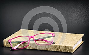 Bright pink glasses on a book