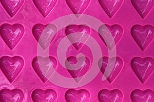 A bright pink heart shaped ice cube or chocolate making tray