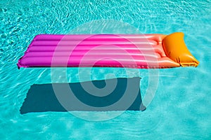 Bright pink inflatable sun bed floating in turquoise pool