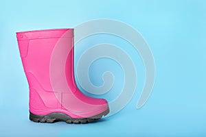 Bright pink rubber boot on light blue background. Space for text