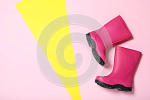 Bright pink rubber boots on color background, top view. Space for text