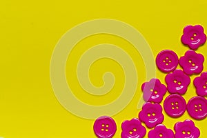 Bright pink sewing buttons on yellow background