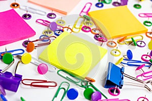 Bright pink, yellow, blue and green stationery accessories for office and education on white background with sticky notes
