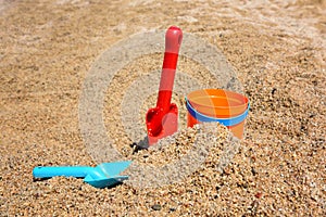 Bright plastic children`s beach toys - bucket and shovels on sand near sea