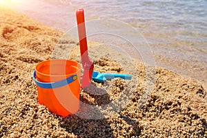 Bright plastic children`s beach toys - bucket and shovels on sand near sea