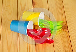 Bright plastic disposable tableware on background of light wood.
