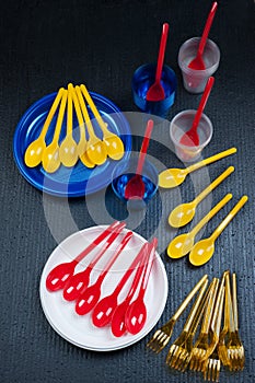 Bright plastic disposable tableware plates, forks, spoons, cups