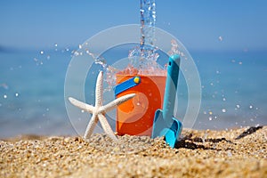Bright plastic Ñhildren`s beach toys and a starfish on sand near sea. Summer vacation concept