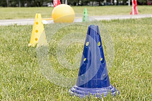 Bright plastic sports cones on the green grass outdoors to train the children`s team.