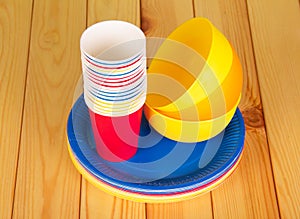 Bright plastic tableware on background of light wood.