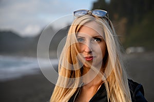 Bright portrait of an attractive blonde woman smiling conservatively by the ocean somewhere at the shores of Northern California