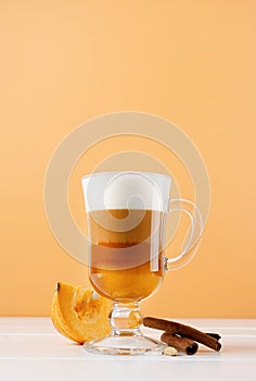 bright pumpkin spice latte in a glass mug with cinnamon