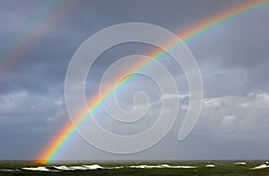 Bright rainbow on the background of storm clouds over the raging sea