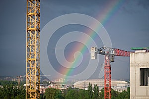 A bright rainbow in the big city. Crane and building construction site